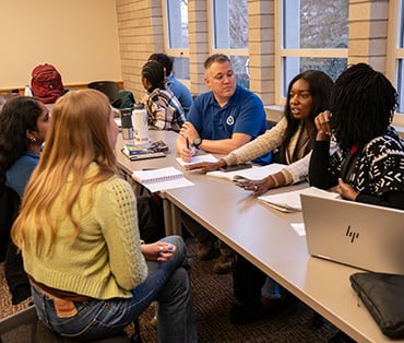 Students talking while seated at a long table