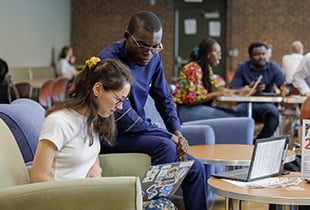 Two students sitting and looking at a laptop screen