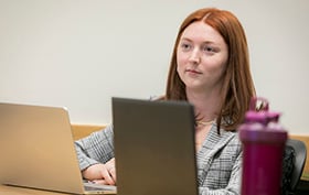 Student seated with a laptop on the table in front of her