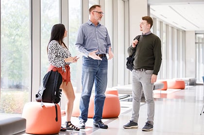 Three people talking in a hallway