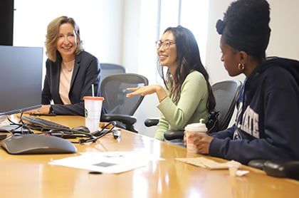 Three women sitting at a conference table and talking