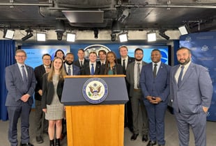 Students behind a podium with the seal of the president of the United States