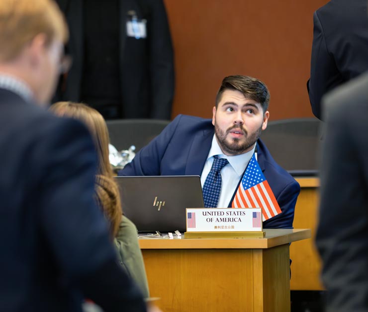 Students at a desk with a US placard and flag