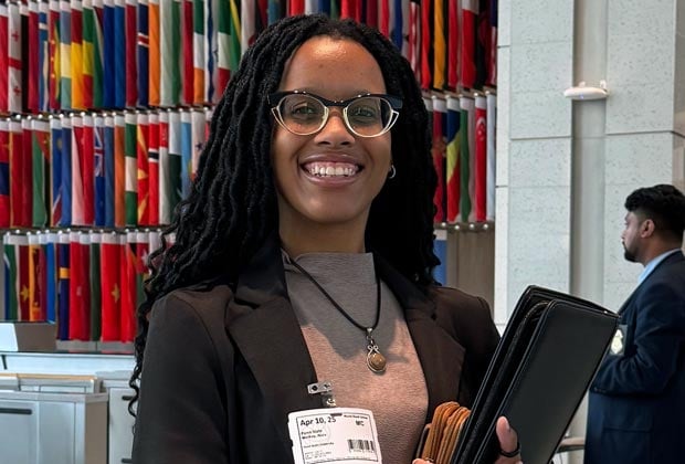 Student smiling, holding a leather binder